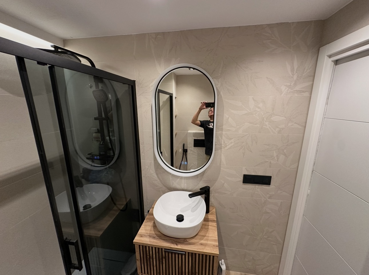 Fotografía real del lavabo sobre mueble de madera y espejo ovalado